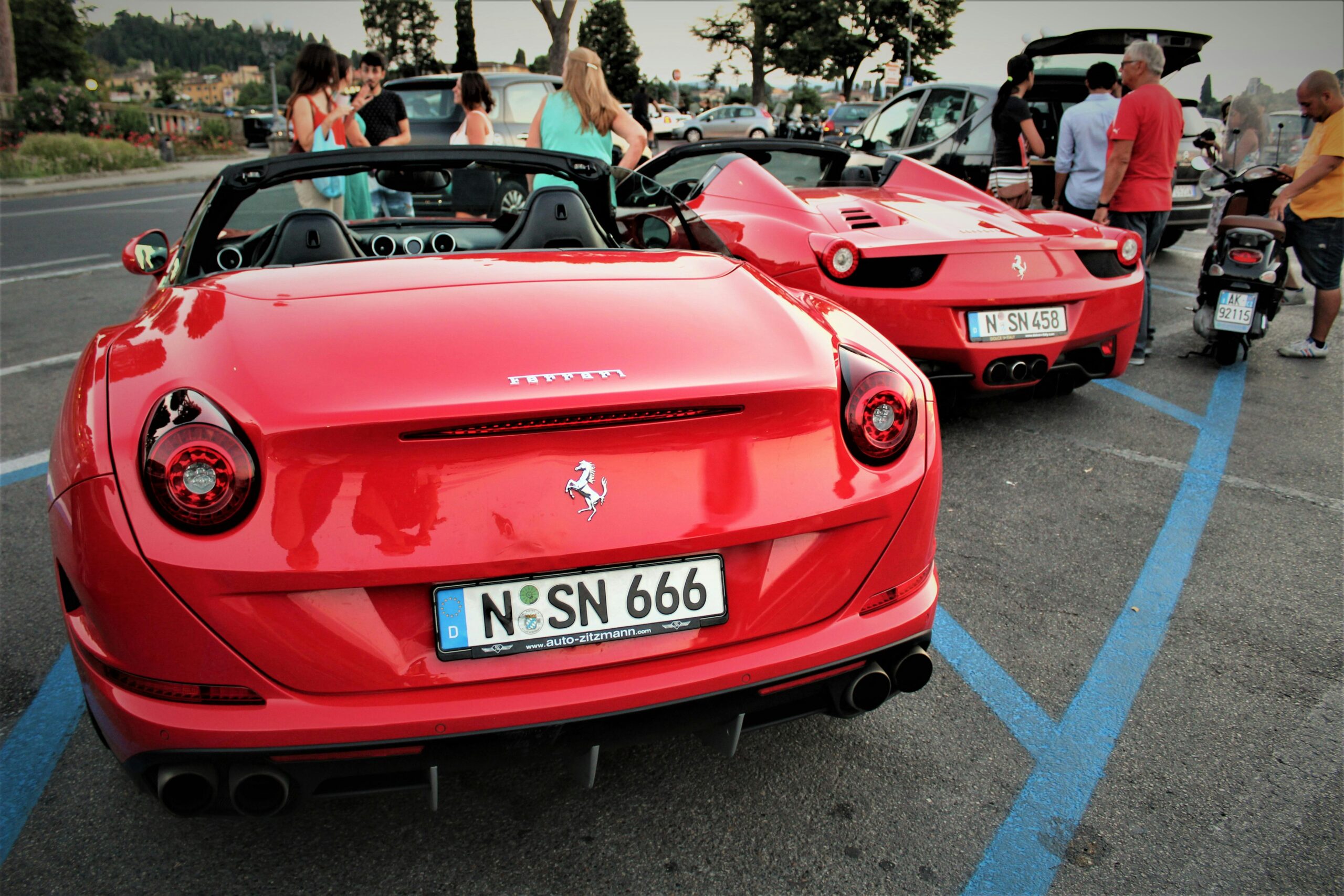 A pair of red Ferrari cars parked outdoors in Firenze, Italy, showcasing luxury automotive design.